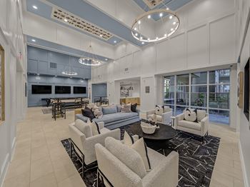 A spacious living room with a black coffee table and grey chairs.